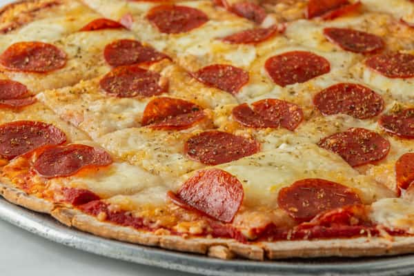 Thin-crust pepperoni pizza topped with melted mozzarella, zesty marinara sauce, and a sprinkle of Italian herbs — a crispy, flavorful classic served on a metal tray.