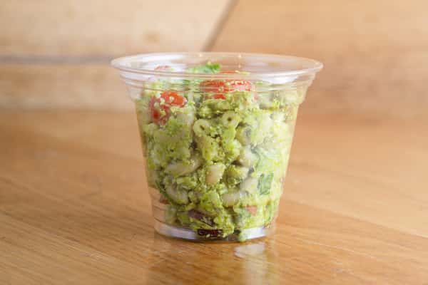 Chicken pesto salad layered with fresh greens, vegetables, and herb pesto dressing in a convenient grab-and-go container.