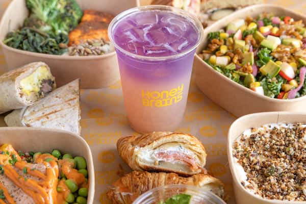 Signature café spread featuring handcrafted pastries, fresh grain bowls, colorful salads, and a refreshing specialty beverage.