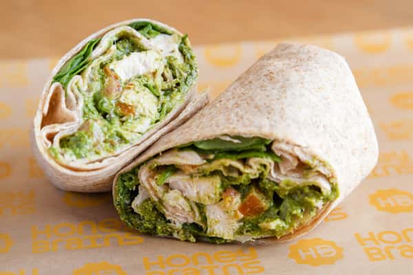 Close-up of a chicken pesto wrap filled with fresh greens, tender chicken, and herb pesto in a wholesome handheld meal.