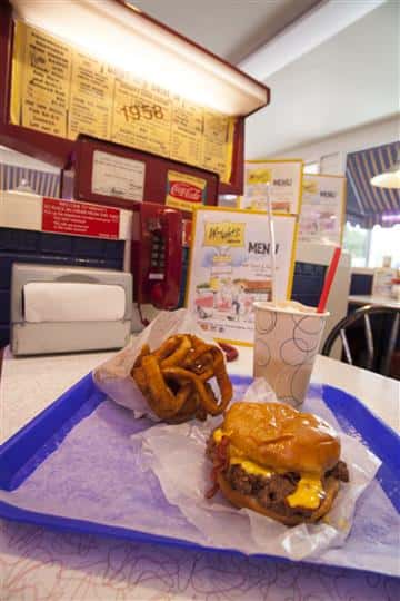 A cheeseburger served with onion rings and a drink on a blue platter