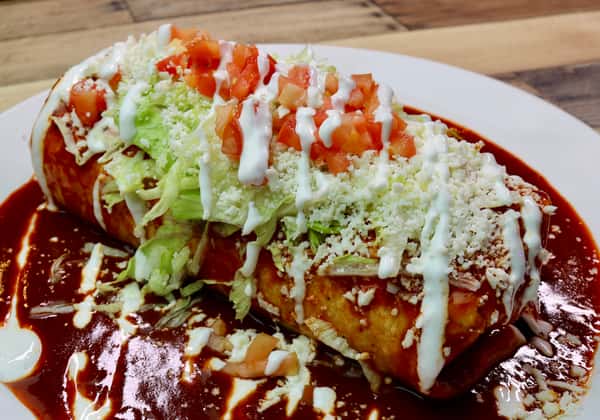 Smothered burrito topped with lettuce, diced tomatoes, crema, and cotija cheese, served over rich red enchilada sauce.