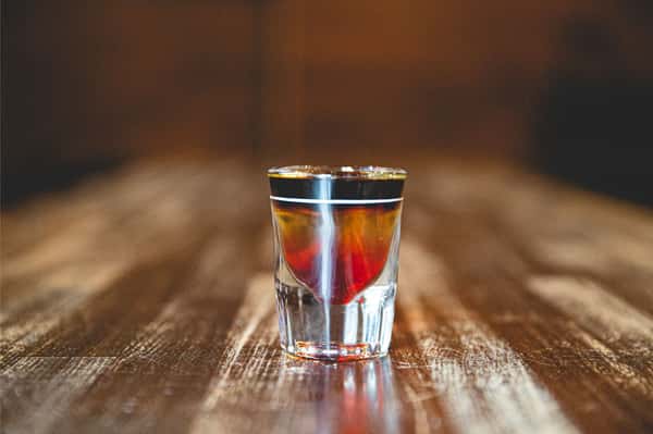 Layered Berlin Bomb specialty shot with vibrant red, gold, and black colors, served as a signature cocktail at Berliner Pub.