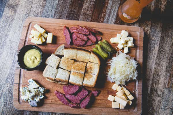 Traditional German charcuterie board with Landjäger sausage, assorted cheeses, pickles, bread, and cured meats at Berliner Pub.