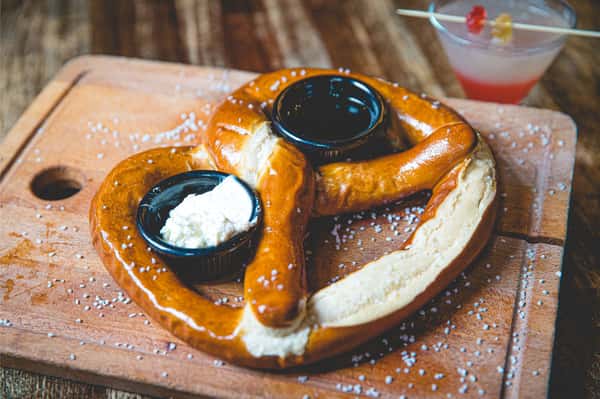 Warm Bavarian dessert pretzel dusted with powdered sugar and served with chocolate and cream dipping sauces at Berliner Pub.