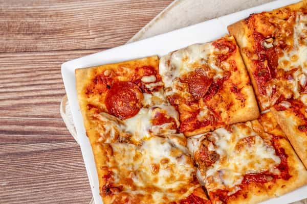 Rectangular pepperoni and cheese pizza slices on a white plate over a wooden table.