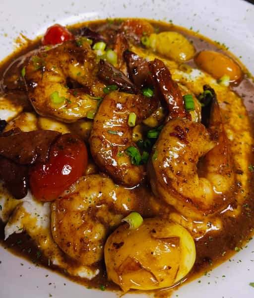 Shrimp and grits topped with rich brown gravy, sausage, cherry tomatoes, and green onions, served with roasted potatoes.