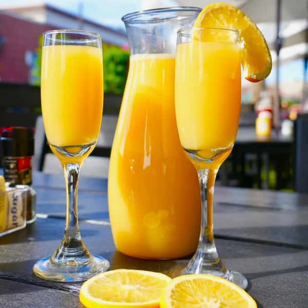 A pitcher of refreshing orange juice accompanied by two glasses, each garnished with a slice of orange.