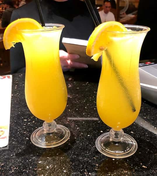 two mimosas on a table with orange slices for garnish