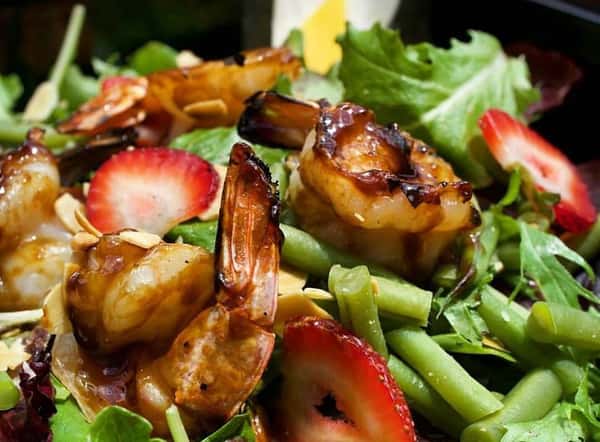 Shrimp over salad with strawberries and green beans