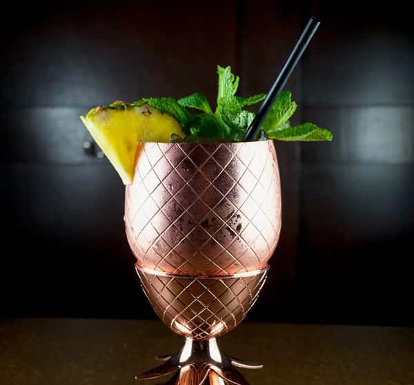 Cocktail in copper cup with mint and pineapple garnish