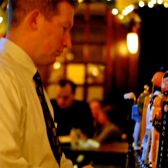 Bartender standing at beer taps