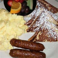 French toast with scrambled eggs, sausages and fruit on the side