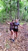 two girls smiling in the woods covering in mud