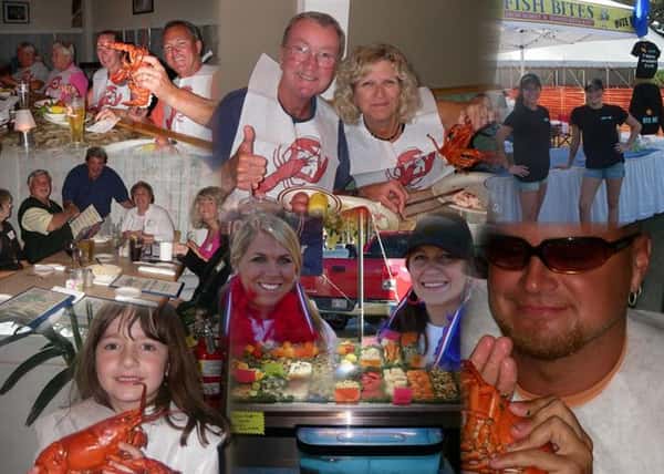 An assortment of customers holding up cooked lobsters and smiling for the camera
