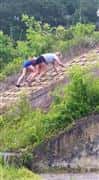 People competing mud run 2015 course by climbing up a rock course