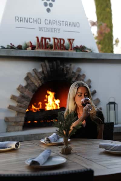 Woman drinking wine in front of outdoor fireplace