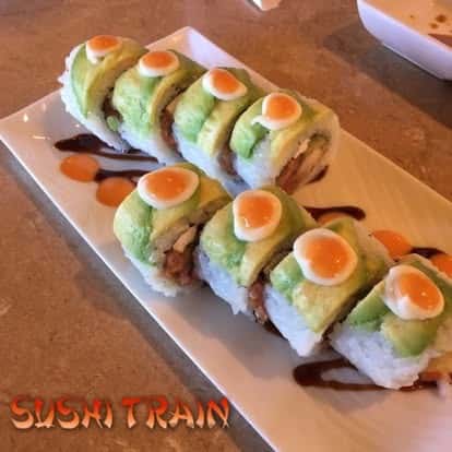 Sushi rolls topped with avocado and roe, served on a rectangular plate