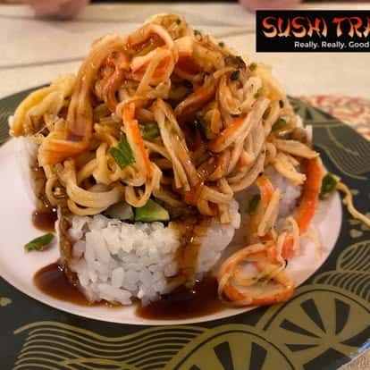 Stir-fried noodle dish served over rice, garnished with vegetables