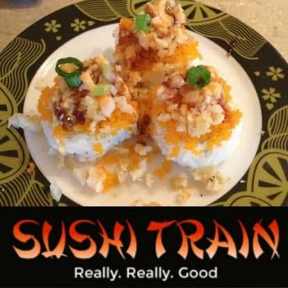Sushi rolls topped with shrimp and orange sauce