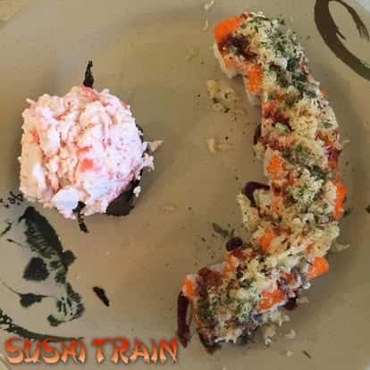 Sushi roll topped with shredded garnish, served on a dark plate