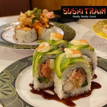 Sushi roll topped with avocado slices and drizzled with sauce