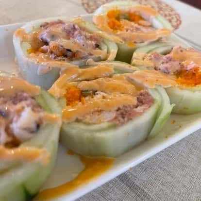 Cucumber-wrapped sushi rolls served with spicy orange sauce