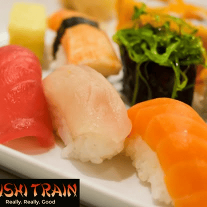 Nigiri sushi platter with assorted fresh fish over rice, garnished with greens