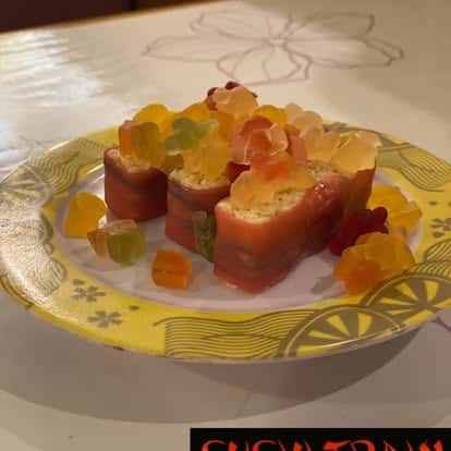 Sushi rolls topped with fresh mango slices, served on a decorative plate
