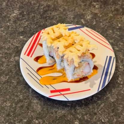 Baked sushi roll topped with melted cheese, served on a colorful plate