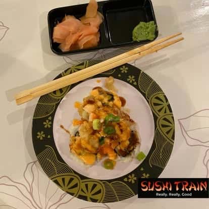 Sushi dish topped with orange sauce, served with chopsticks