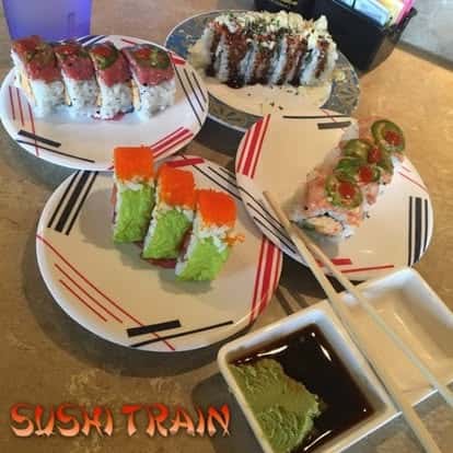 Assorted sushi rolls served on colorful plates with dipping sauces