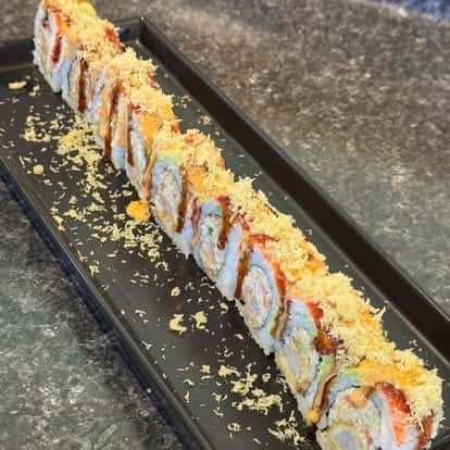Long sushi roll topped with orange sauce and garnish