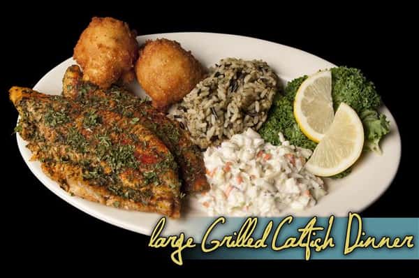 large grilled catfish dinner with rice and hush puppies