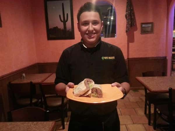 server holding plate of food and smiling.