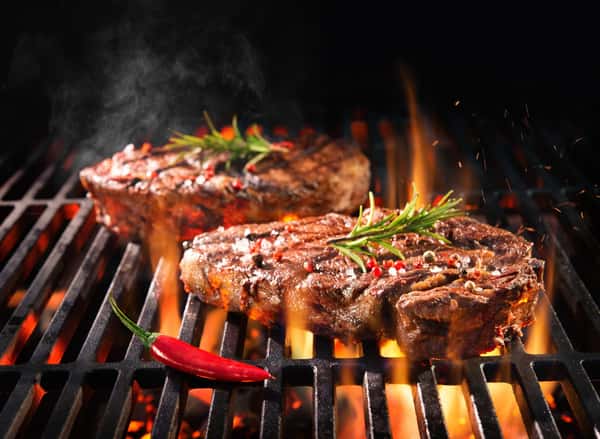 Grilled steaks with rosemary, red pepper, and flames at City Limits Bar and Grill.