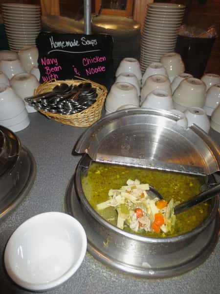 Soup buffet at City Limits Bar & Grill features homemade navy bean and chicken noodle soups, with white bowls and stacked plates.