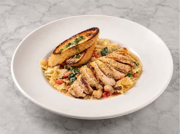 Grilled chicken pasta tossed in a creamy seasonal sauce with roasted vegetables and garlic crostini at Local on North, offering chef-driven Southern-inspired dining.