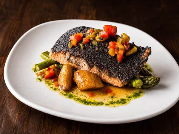 Poppy seed crusted salmon with roasted potatoes, grilled asparagus, and house-made herb sauce at Local on North, featuring fresh seafood and Southern-inspired flavors.