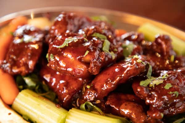sticky barbecue chicken wings glazed in rich sauce with celery and carrot sticks garnish