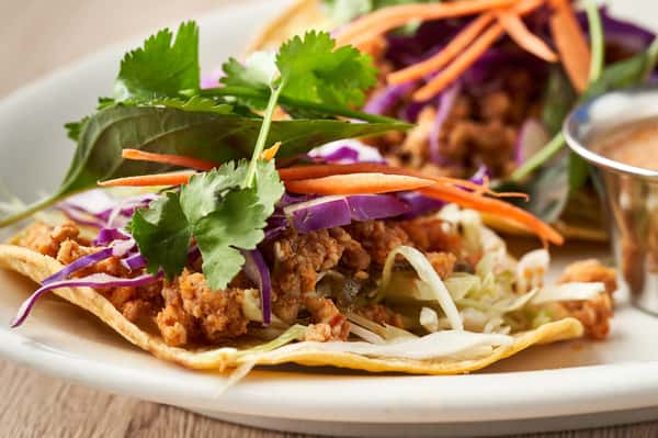 Tacos topped with seasoned meat, fresh vegetables, and cilantro.