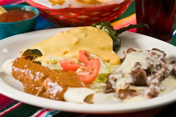 Combination of Mexican dishes served in a plate topped with sauces and served with garnish