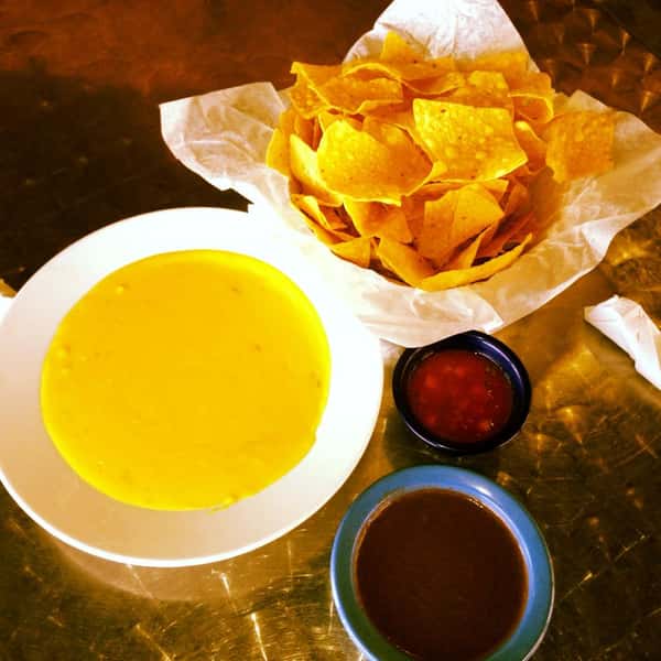 Basket of tortilla chips served with three dipping sauces