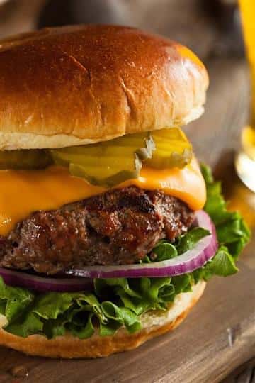 Cheeseburger with pickles red onion and lettuce on a bun