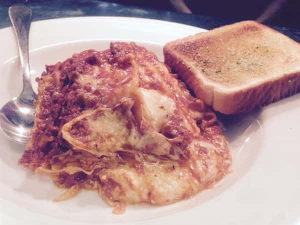 Pasta with sauce. Melted cheese over the top with a side of garlic bread