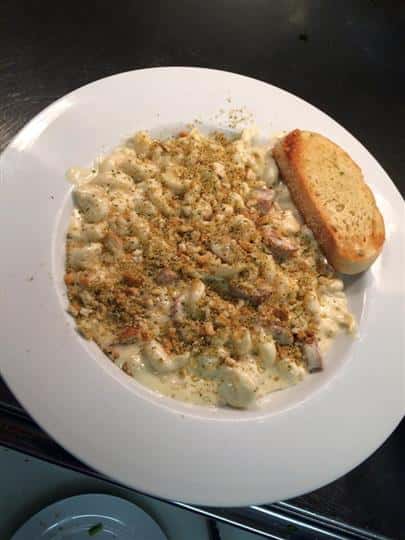 Mac and cheese with sausage and breadcrumbs with garlic bread on the side