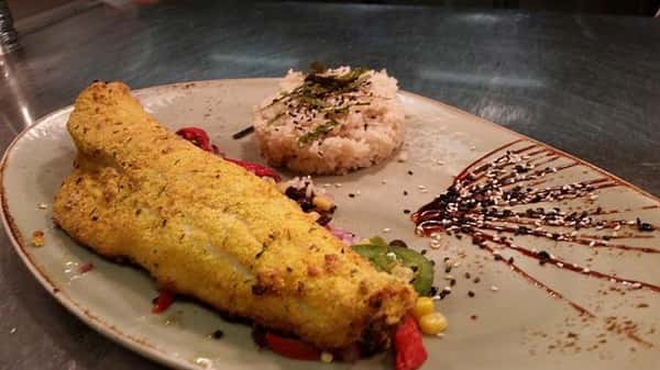 Fried fish over peppers, onions and corn with side of rice