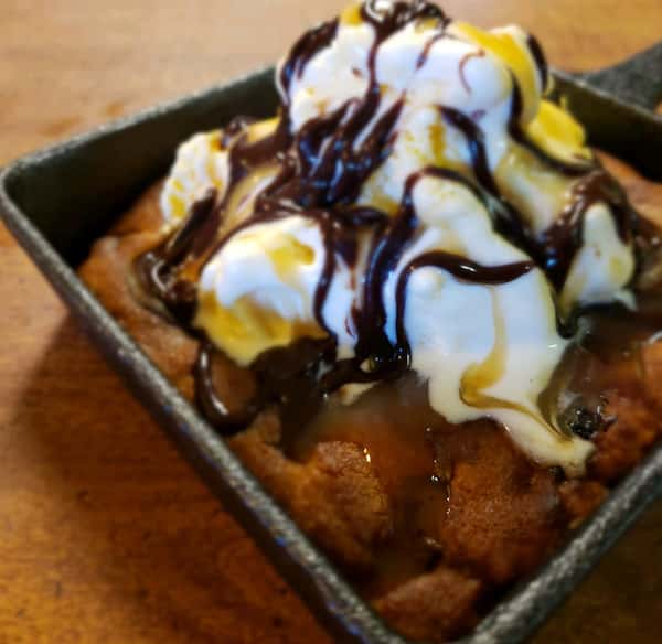 crumbcake skillet with whipped cream and chocolate drizzle