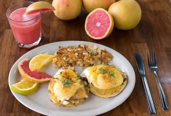 Eggs Benedict served with breakfast potatoes and fresh fruit.