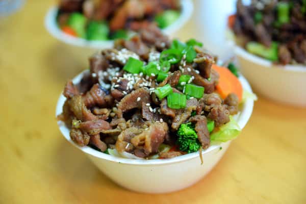 tender teriyaki beef topped with chopped green onions, served over rice with fresh vegetables for a satisfying meal.